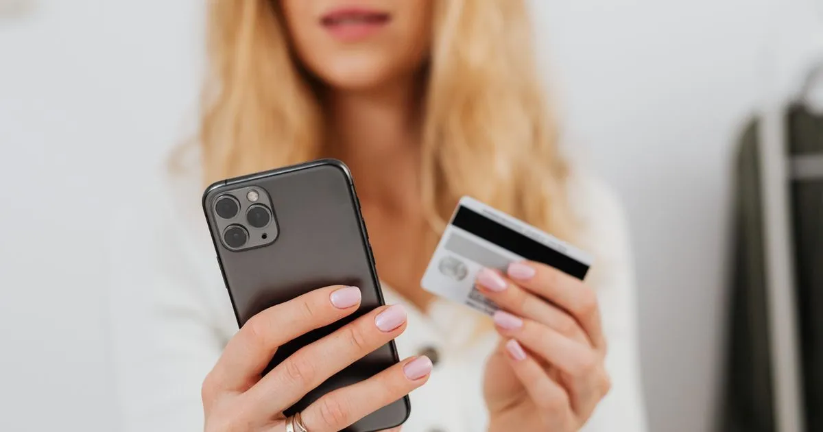 スマートフォンとクレジットカードを手に持ってネットで買い物をしている手元