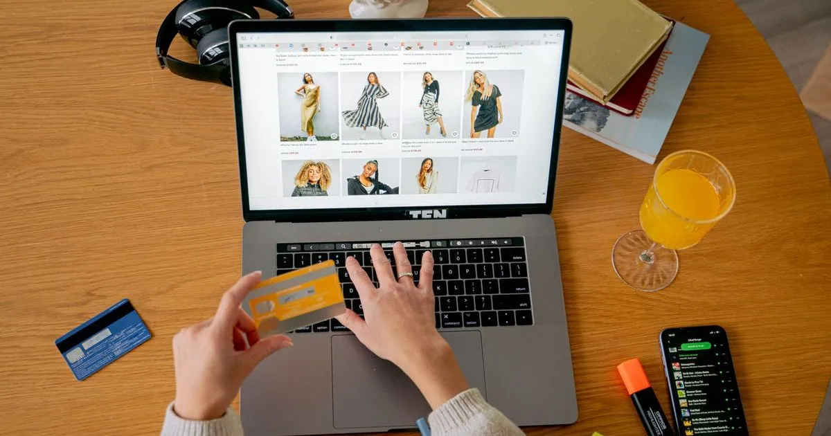 ノートパソコンでECサイトを見ながらクレジットカードを手にしている手元