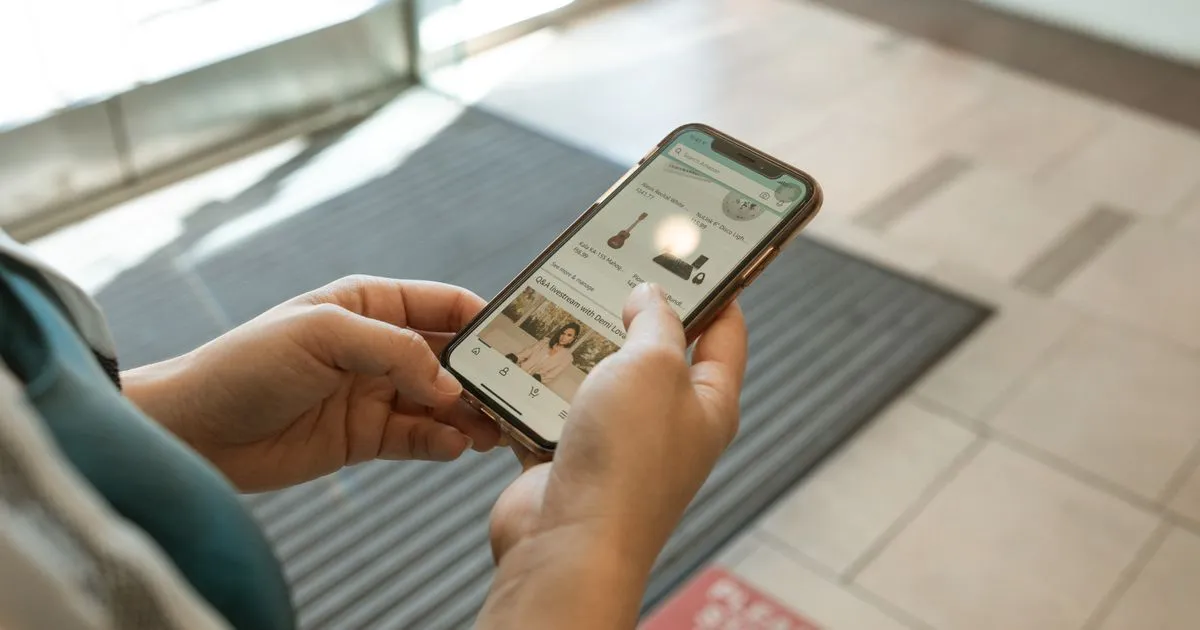 スマートフォンでショッピングアプリの商品一覧を見ている手元