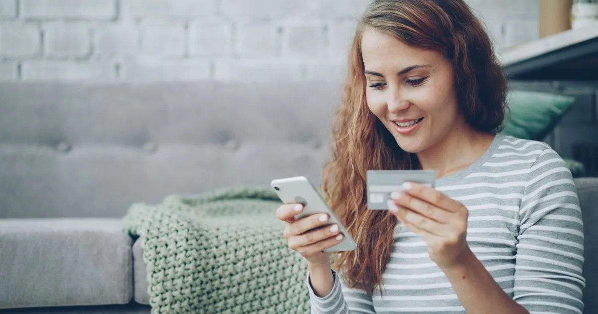 スマートフォンとクレジットカードを手にオンラインで買い物をしている女性